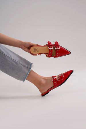 The vibrant red SWIRL-01 Buckled Slip-On Flats from Beast Fashion are displayed being held, emphasizing their sleek pointed toe and buckle details. These buckled slip-on flats are ideal for new shoe lovers and summer outfits. Mules that are a fashion must-have.