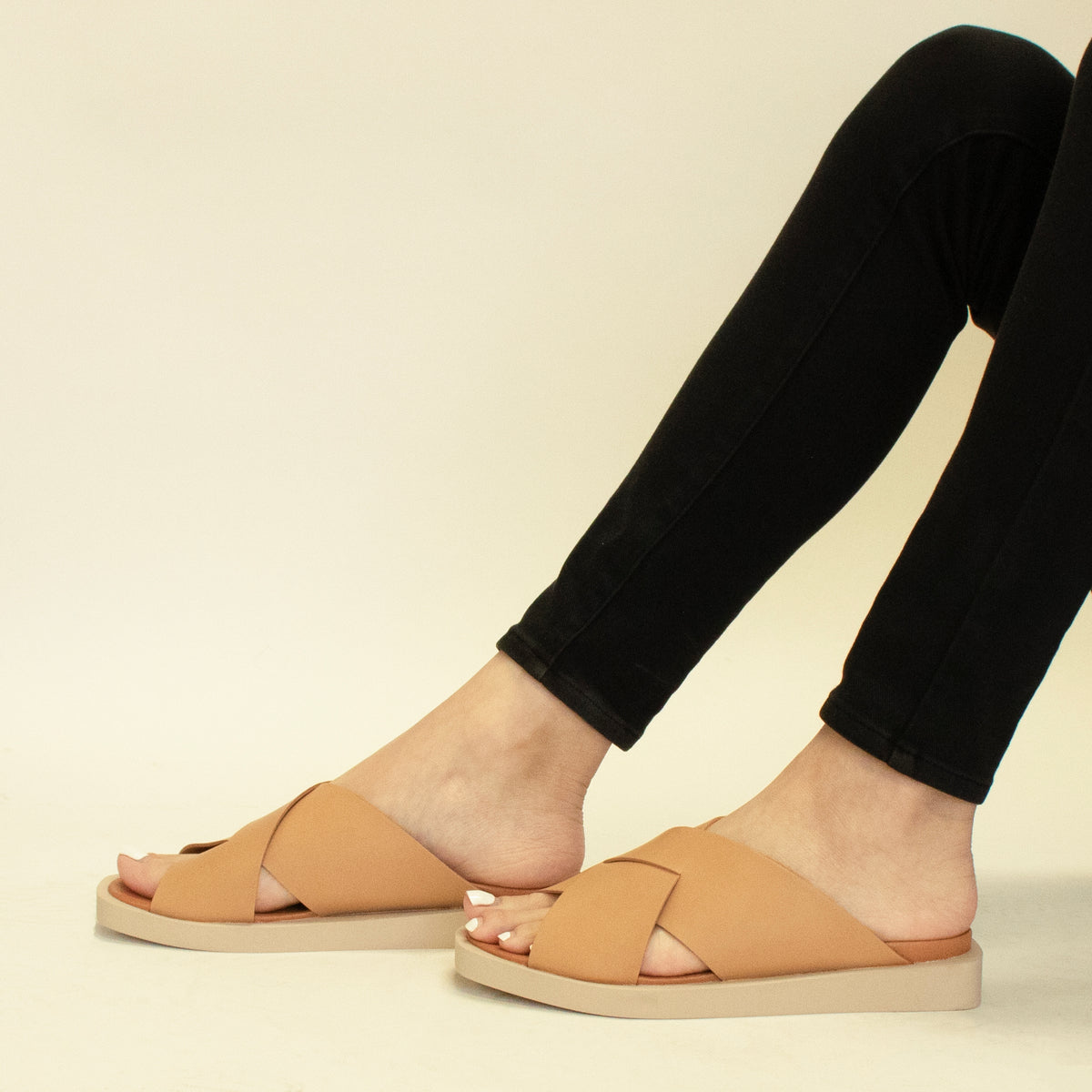 Feet wearing VICENTE-09 Crisscross Flat Sandals by Beast Fashion in beige. Ideal for summer vacations, these stylish slide sandals feature a comfortable design perfect for casual day outs.